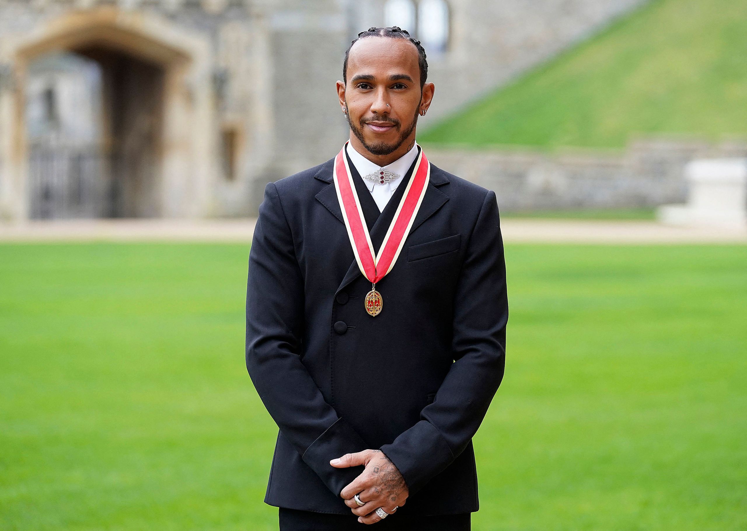 Mercedes' British F1 driver Lewis Hamilton poses with his medal after being appointed as a Knight Bachelor  for services...