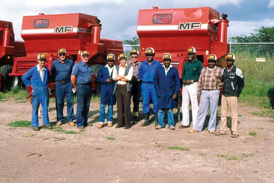 Local farmers in Africa standing beside farm equipment