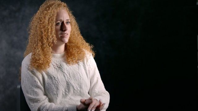 Anneka pictured in BBC studio interview, wearing white jumper