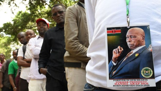 A man wearing a badge with the photo of late former Kenyas President Daniel Arap Moi, queues to view his remains